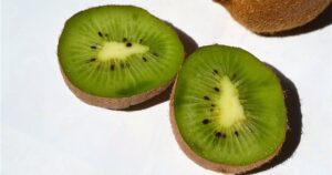Green kiwifruit cut in half showing bright green flesh, white core and black seeds