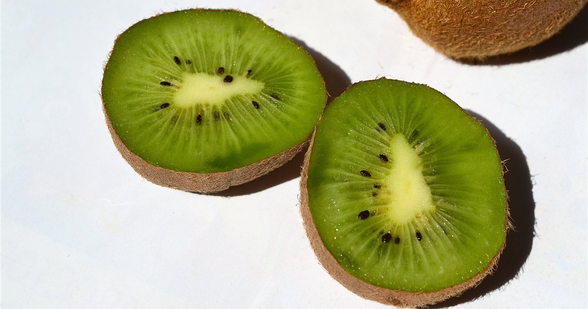 Green kiwifruit cut in half showing bright green flesh, white core and black seeds